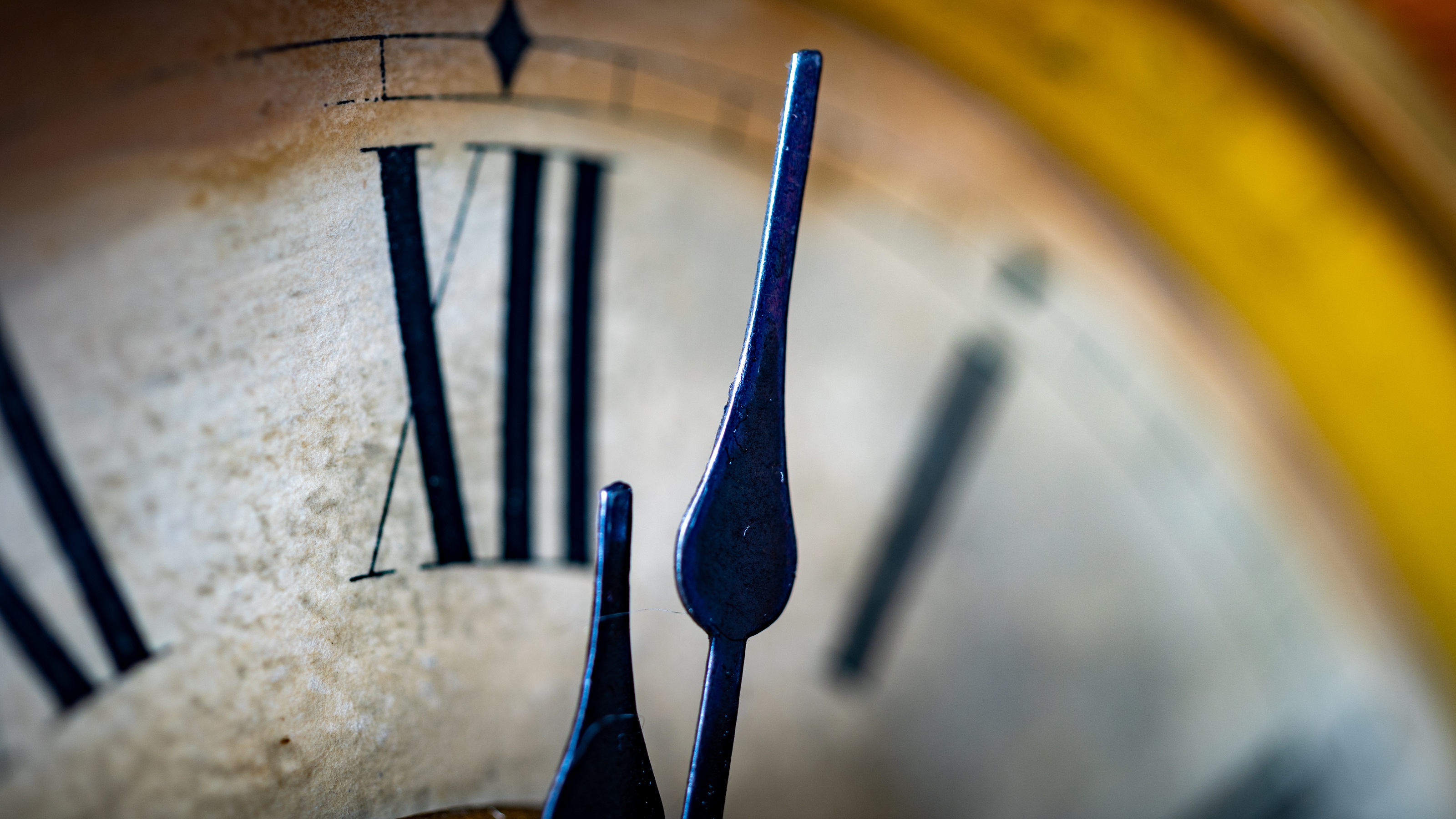 Close-up of a clock with Roman numerals on a dark background.