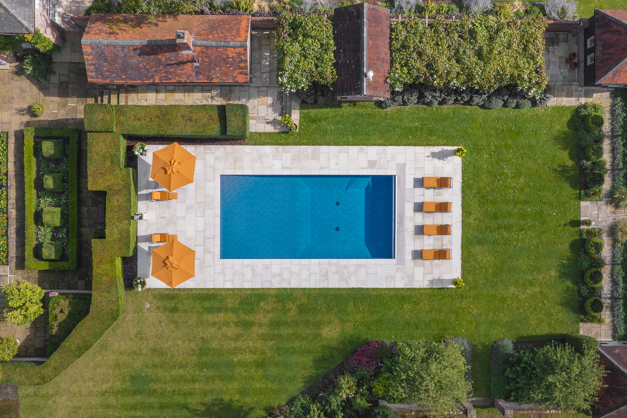 Bird's eye view of a luxury swimming pool surrounded by green lawn.