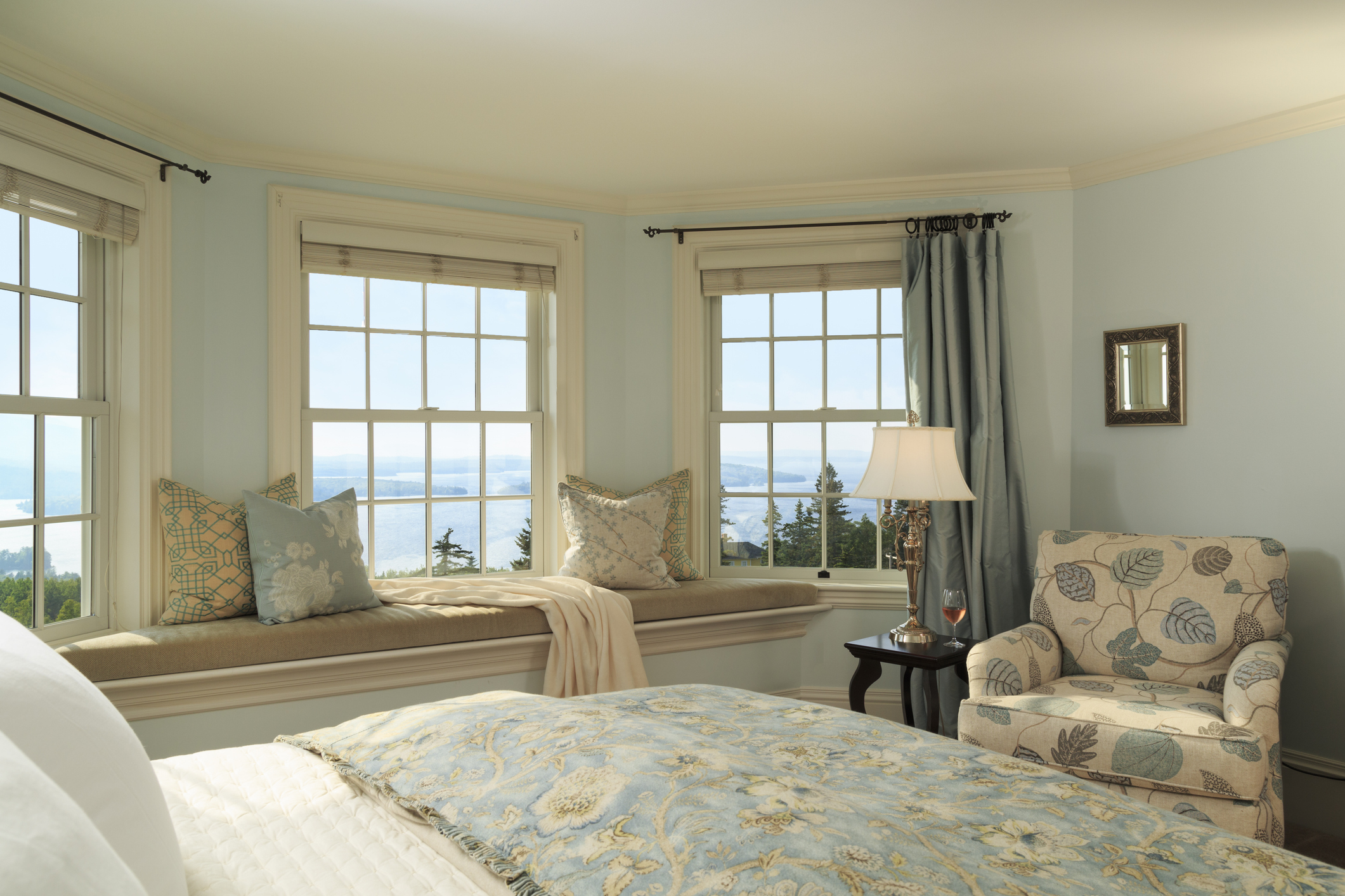 A well-lit bedroom with a lake view from a window seat in the Moosehead Lake Area.