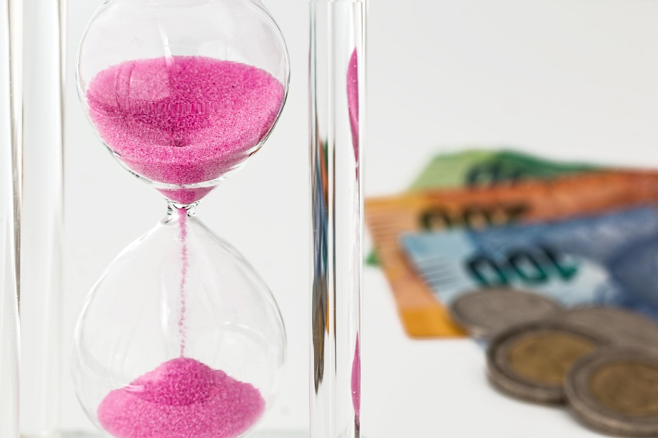 An hourglass standing next to legal documents and currency