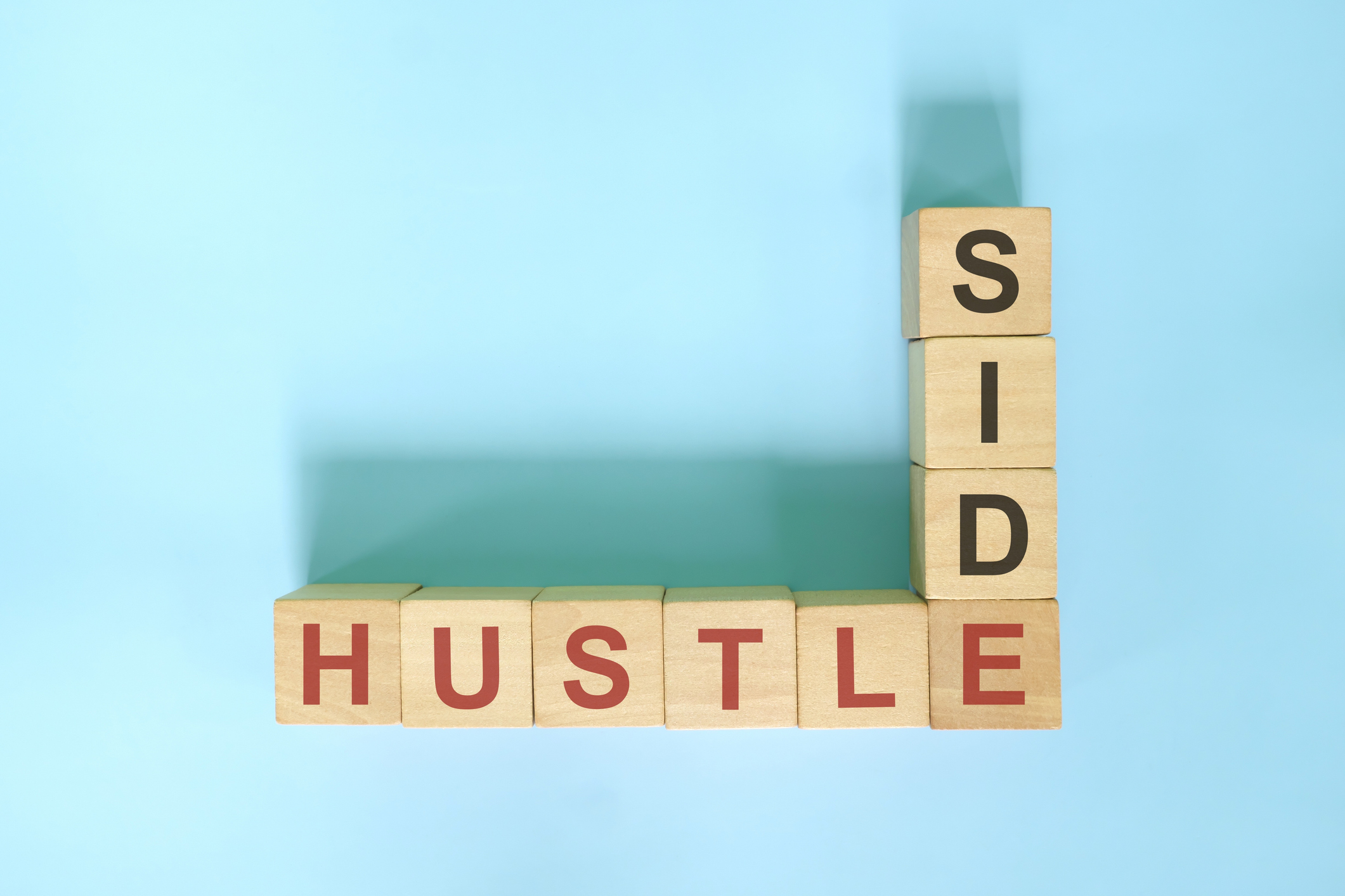 Wooden blocks spelling out the words 'side' and 'hustle' in a crossword format.