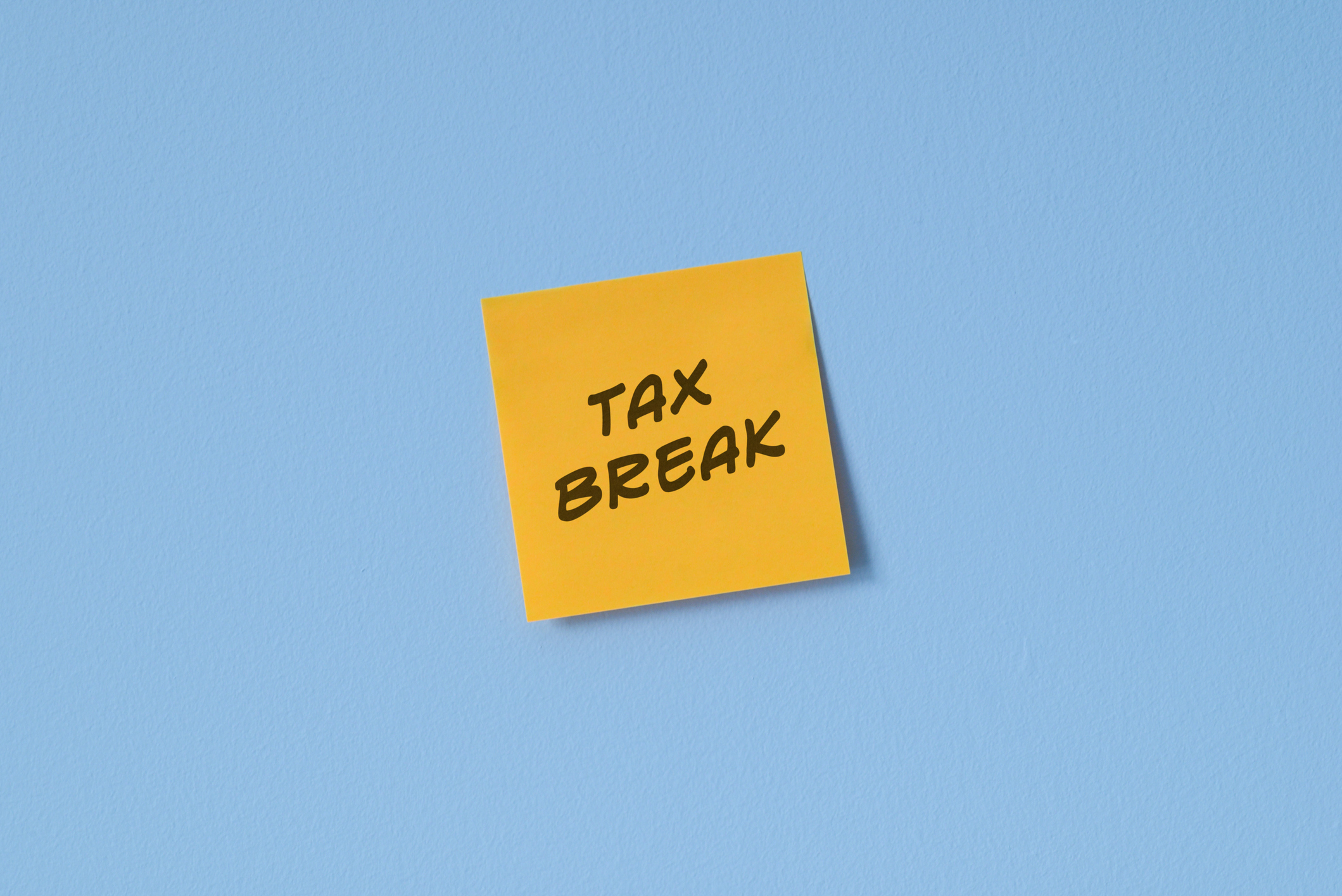 A yellow post-it note on a blue background with the handwritten words 'Tax break'.