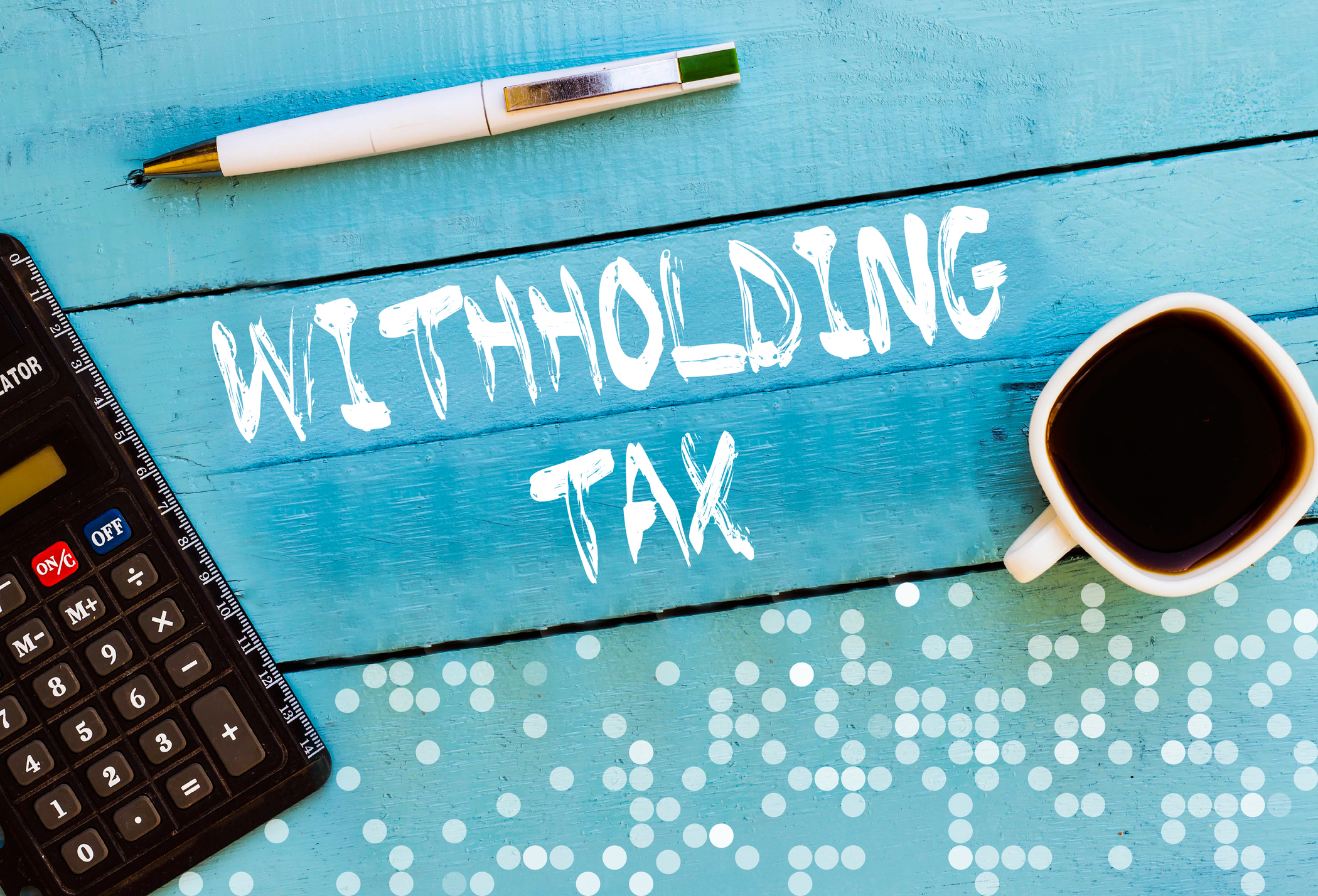 A blue desk surface with a calculator, a pen, a cup of coffee, and a document labeled 'Withholding tax'.