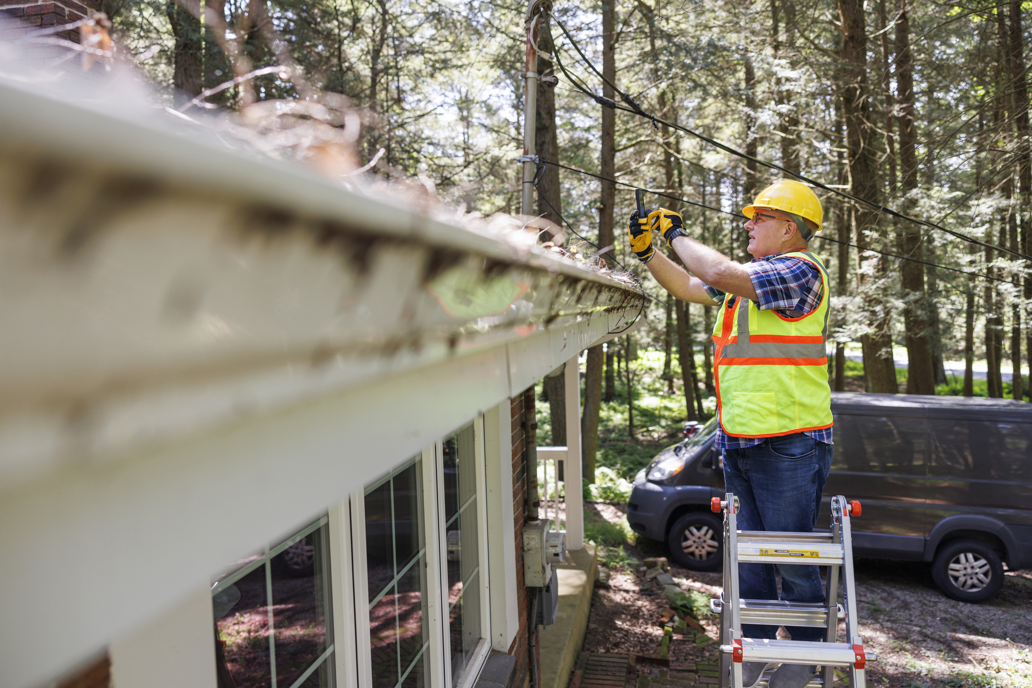 A professional in high-visibility gear taking photos of a roof surface.