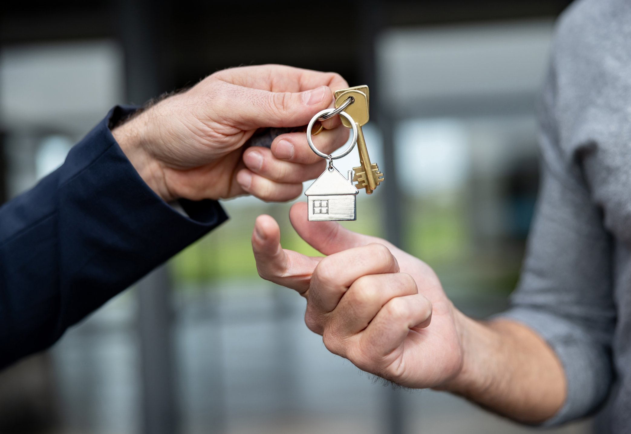 Close-up of a hand passing house keys to another person.