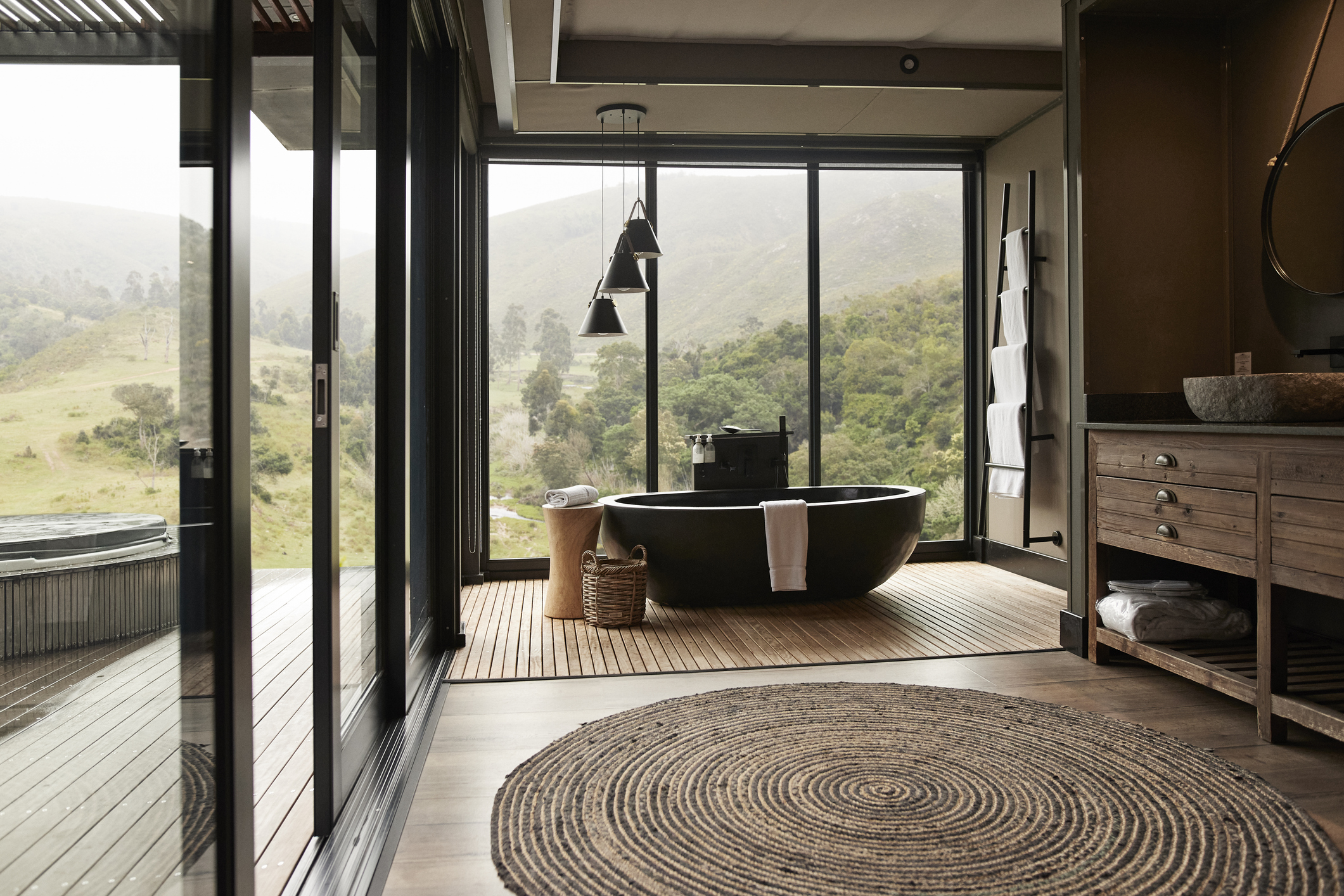 A decorative pendant light hanging over a bathtub in a modern bathroom.