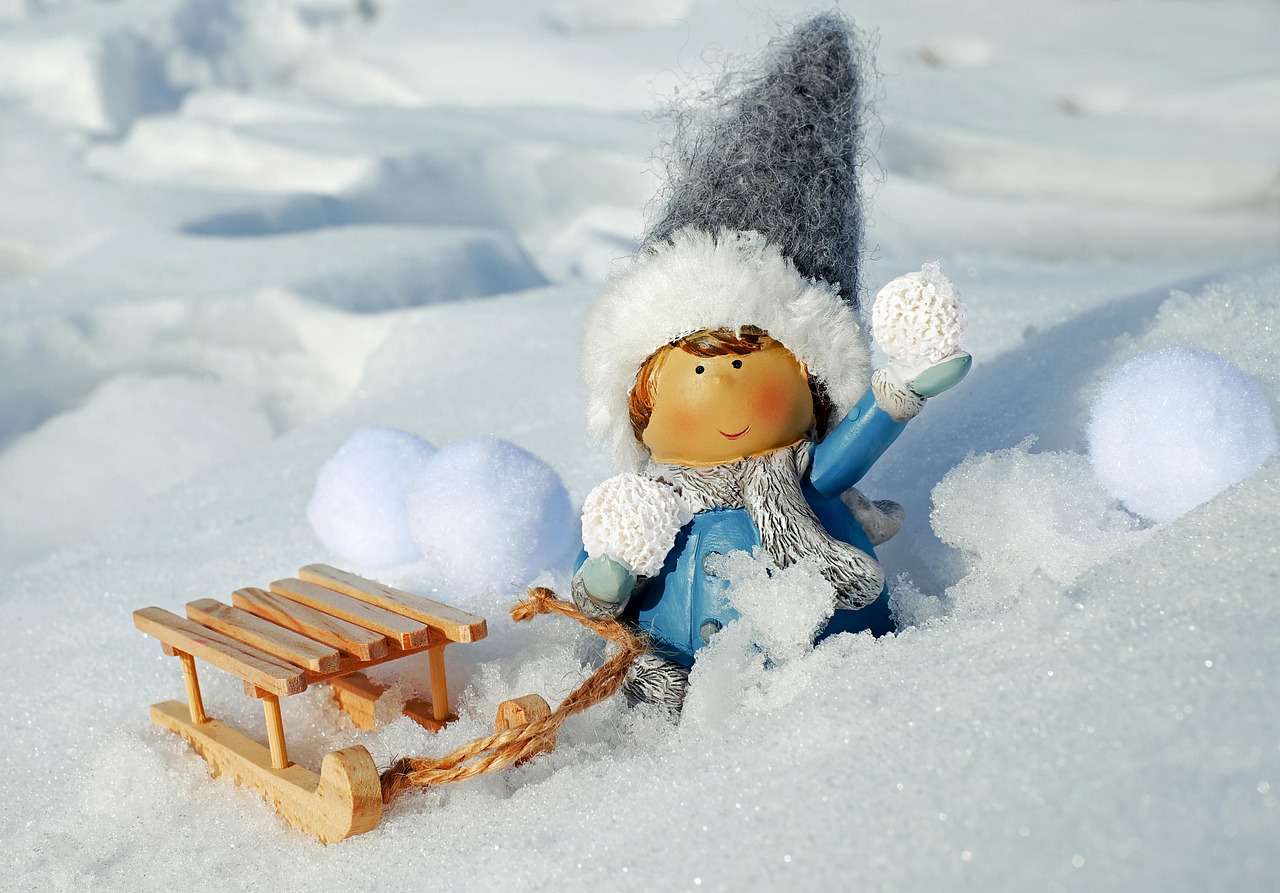 A person's hands rolling a small snowball in a bright winter field to represent momentum.