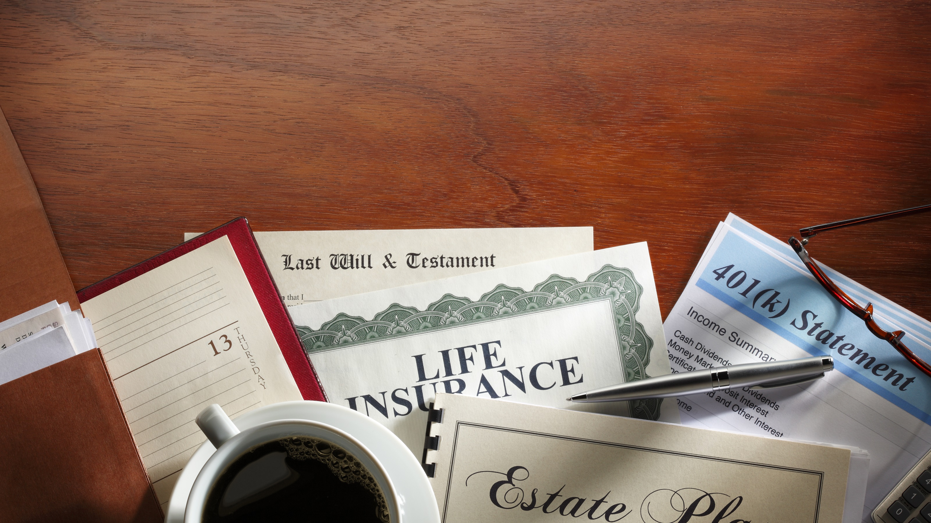 Documents titled Last Will and Testament and Estate Planning on a wooden desk with a pen.