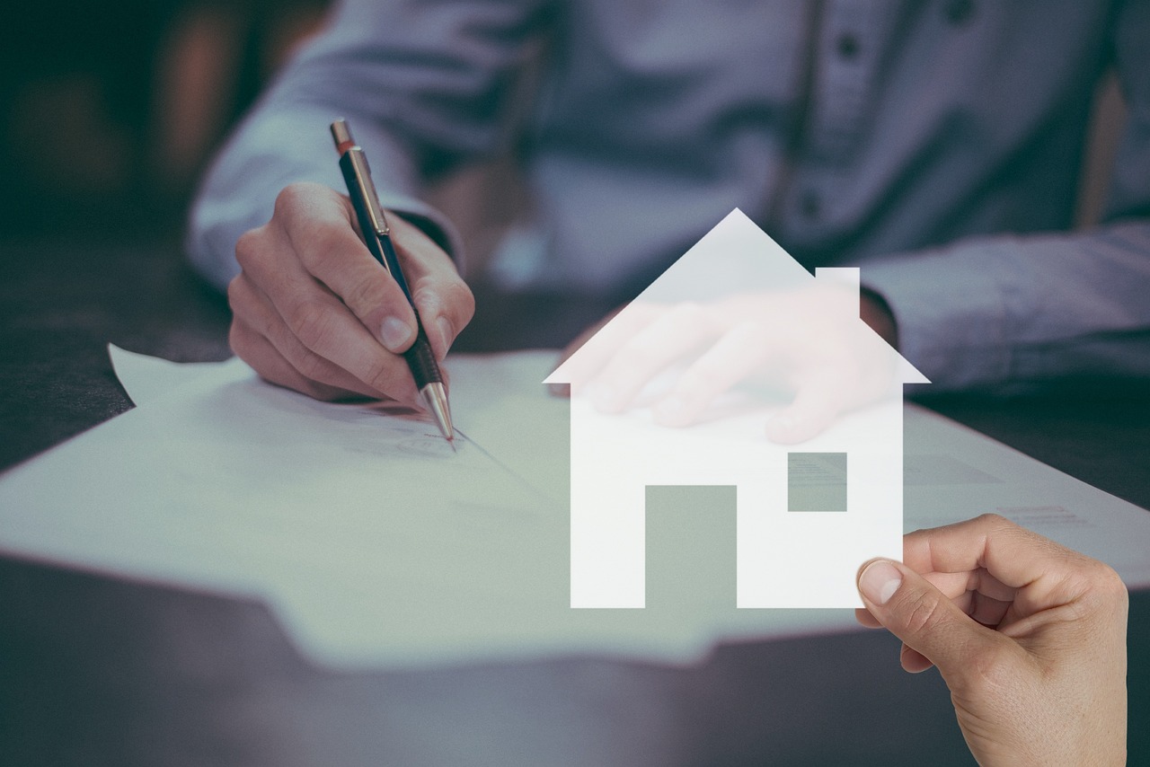 Close up of house keys laying on top of a loan agreement and a pen.