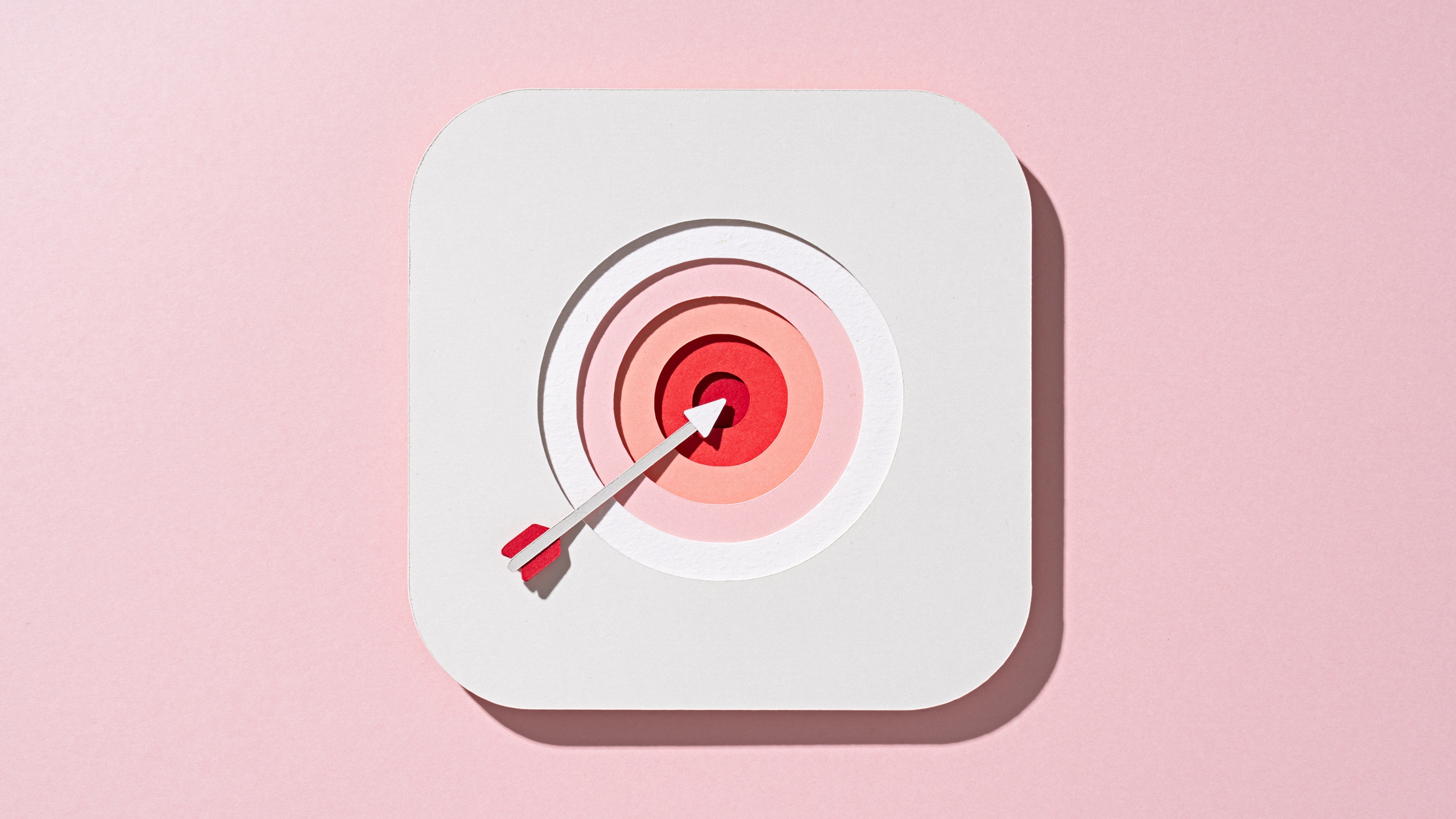 A white arrow hitting the center of a black bullseye on a pink background.