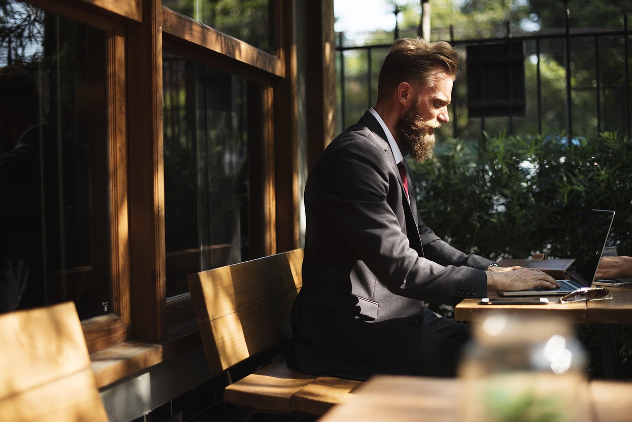 A person working on a laptop with a world map icon in the background representing remote work.