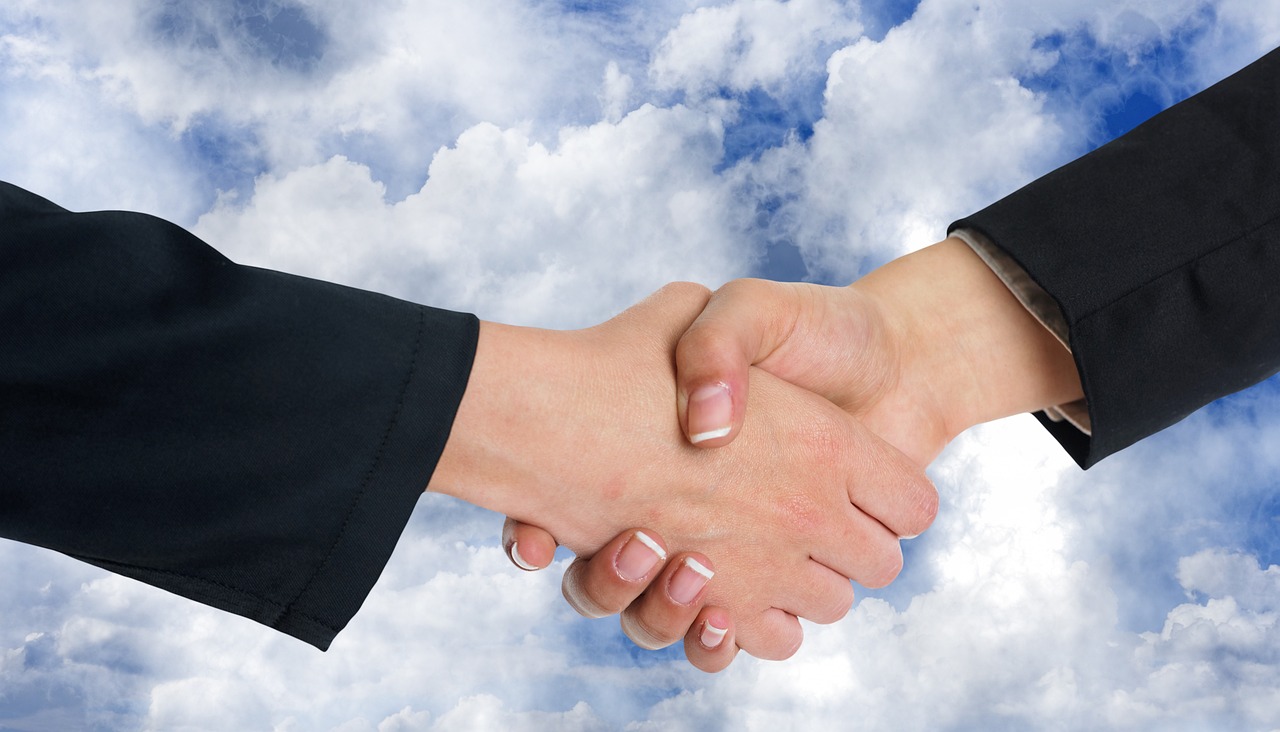 Two people shaking hands over a signed settlement agreement letter.