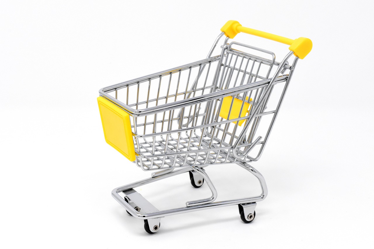 A shopping cart filled with grocery bags and a long receipt.