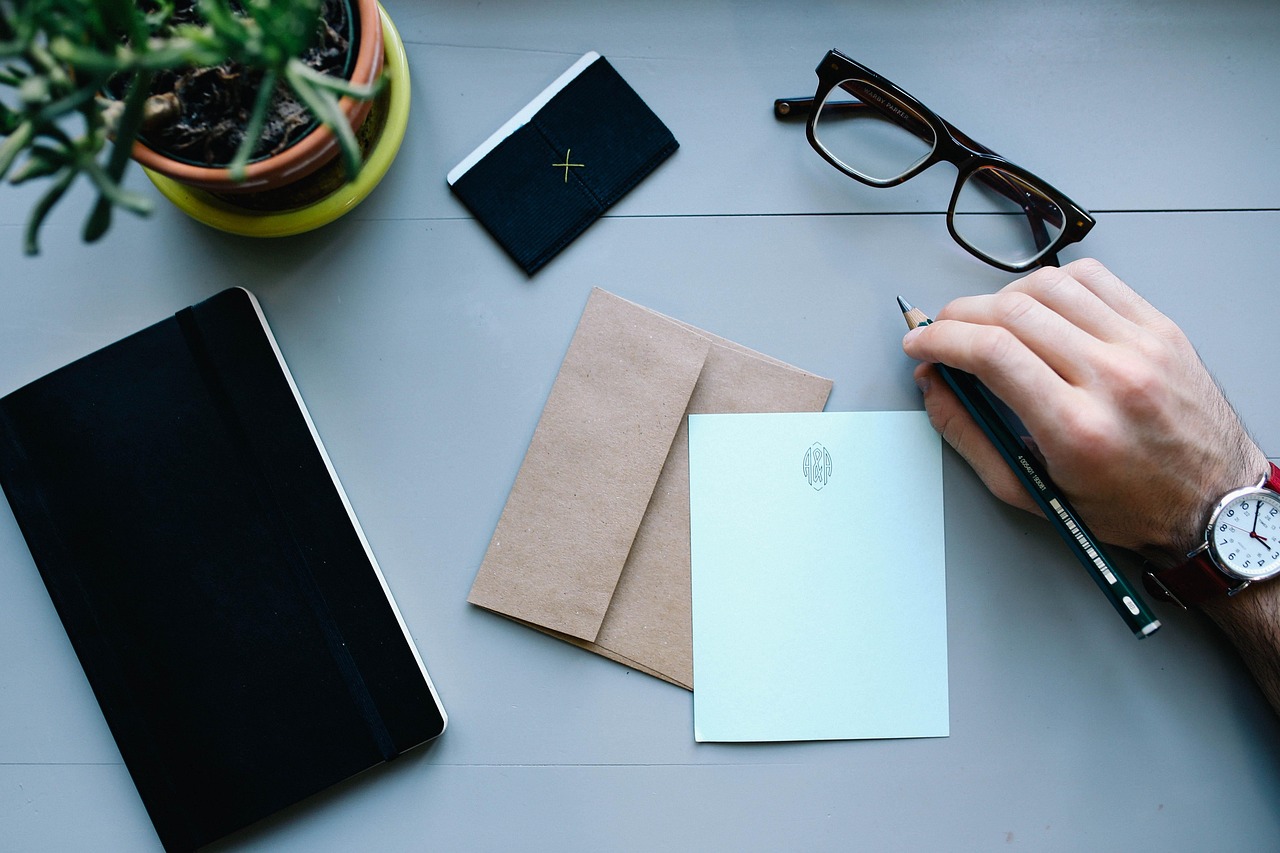 A person carefully filling out legal paperwork on a wooden desk with a pen.