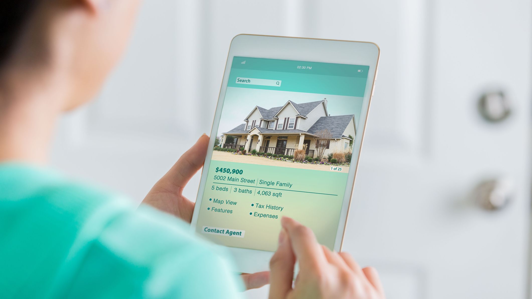 A person using a digital tablet to browse property listings and market data.
