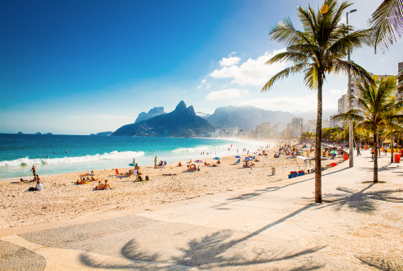 A wide view of Ipanema beach in Rio de Janeiro with the Two Brothers mountains in the background.