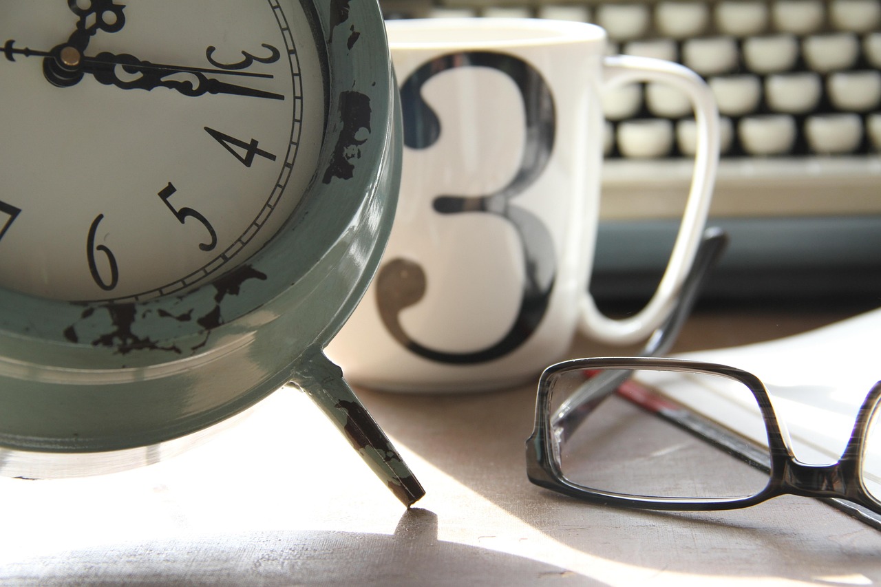 An hourglass standing on a desk next to a calendar representing long-term financial history.