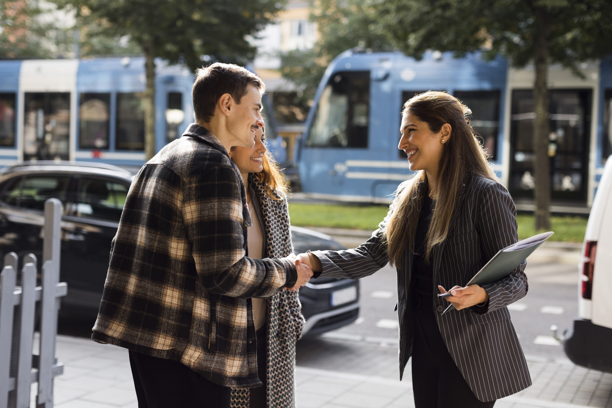 A buyer and real estate agent shaking hands in front of a residential property.