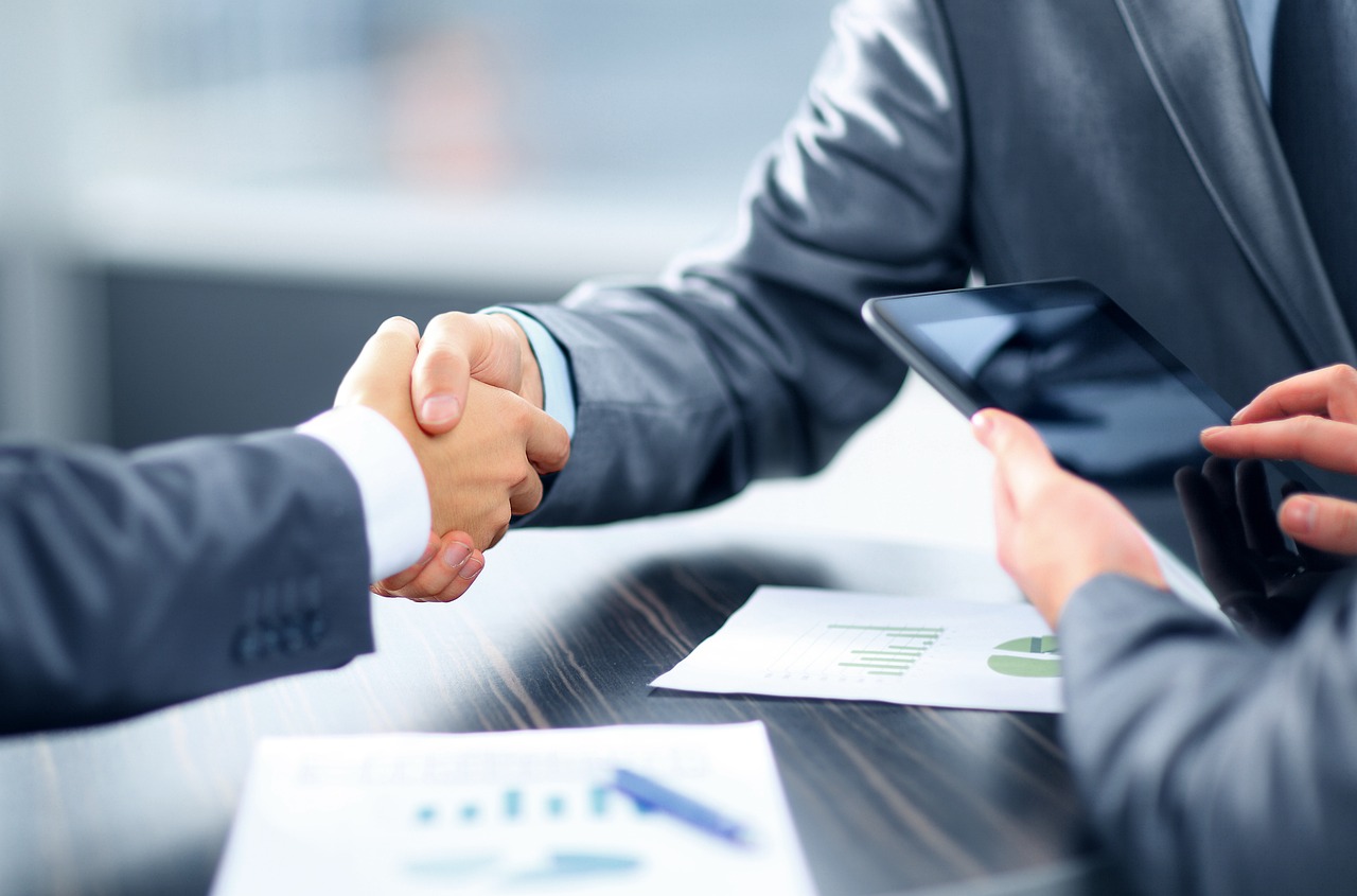 A professional desk setting with documents and a symbolic handshake for financial agreement.