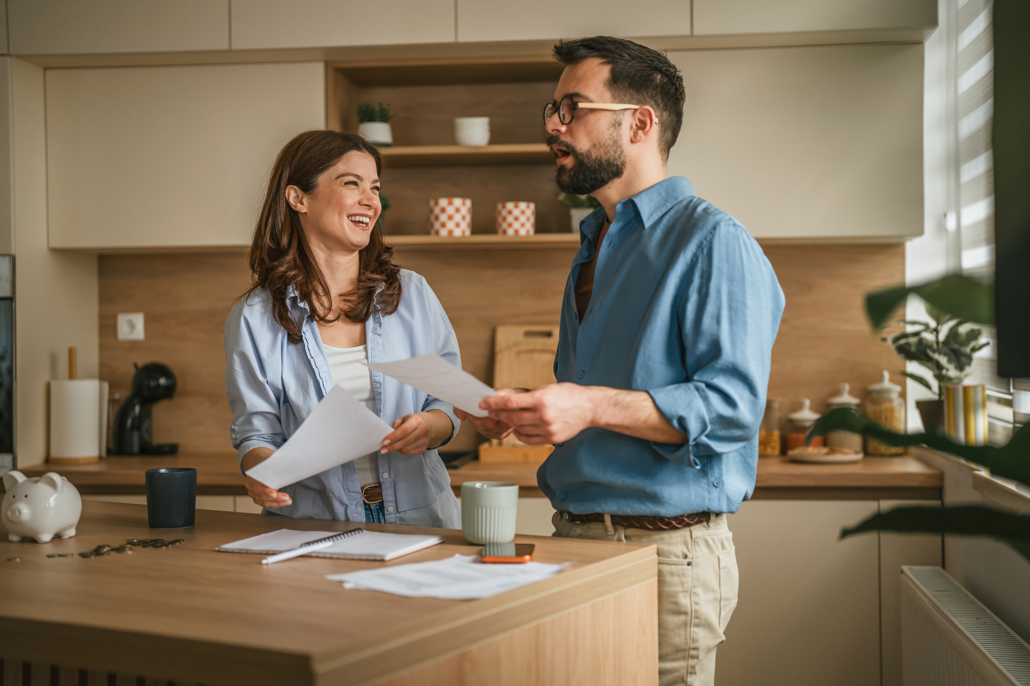 A couple sitting at a table with a laptop, looking at financial documents together.