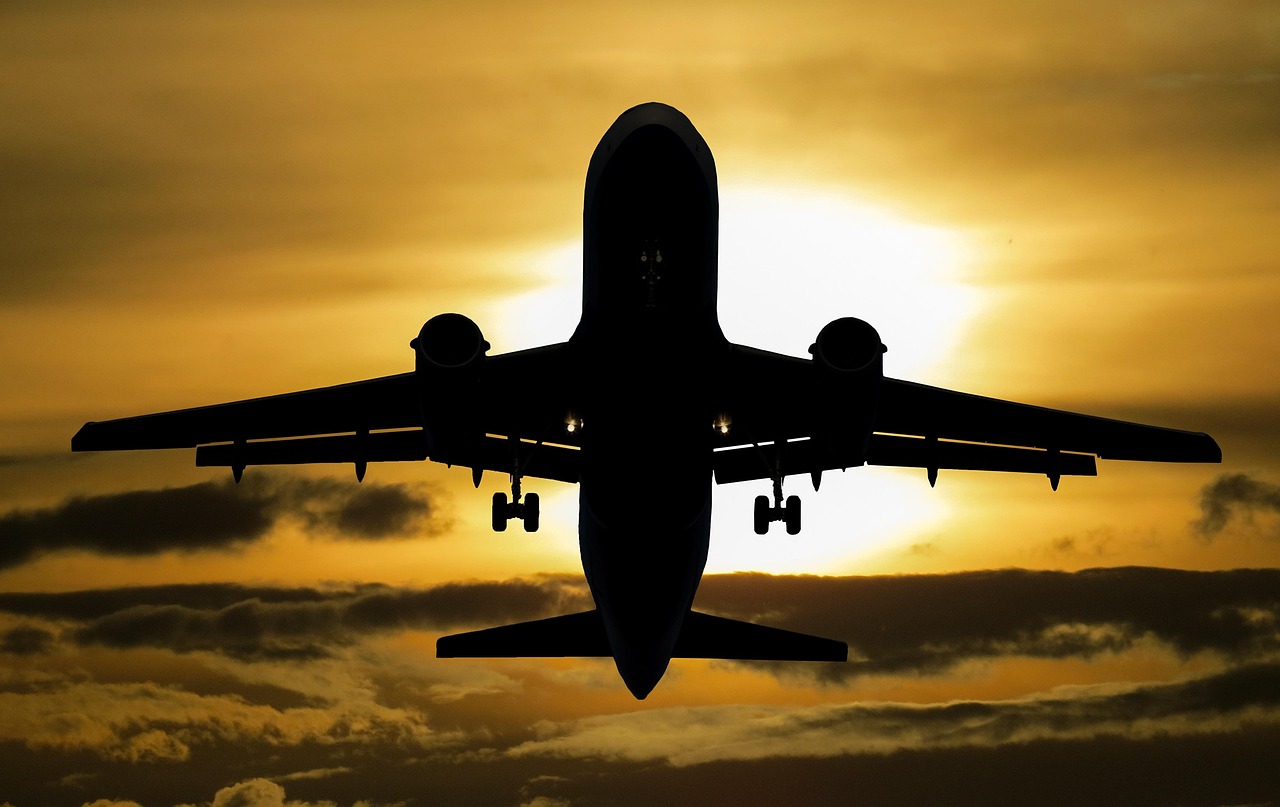 A view of the airplane wing flying above clouds during a golden sunset