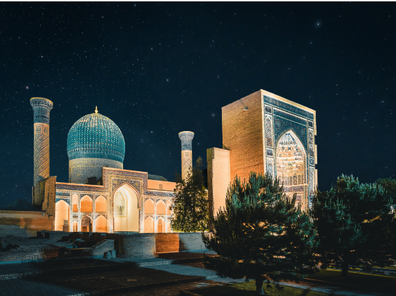 The Gur Amir mausoleum in Samarkand illuminated at night, showing its turquoise tiled dome.