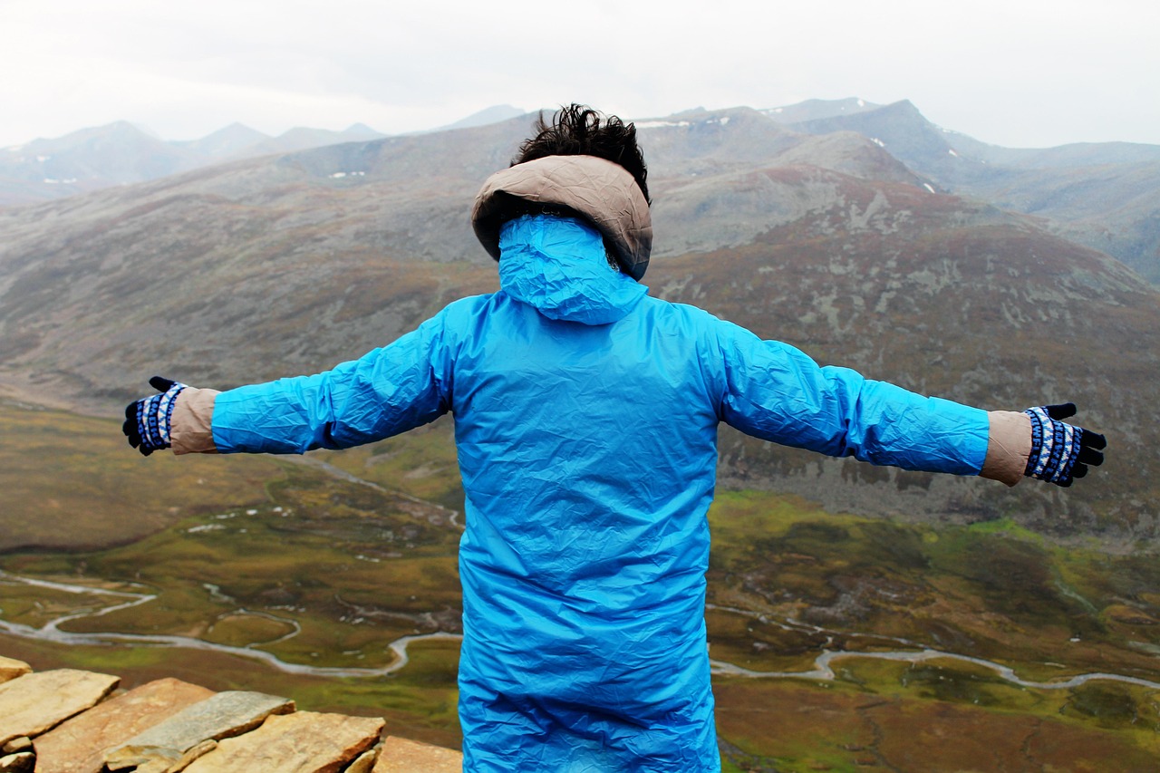 A confident young man standing on a mountain peak, representing a bright future.