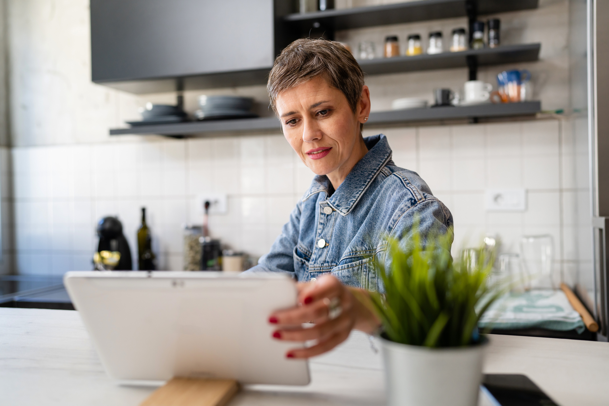A woman using a tablet device in a modern home kitchen.