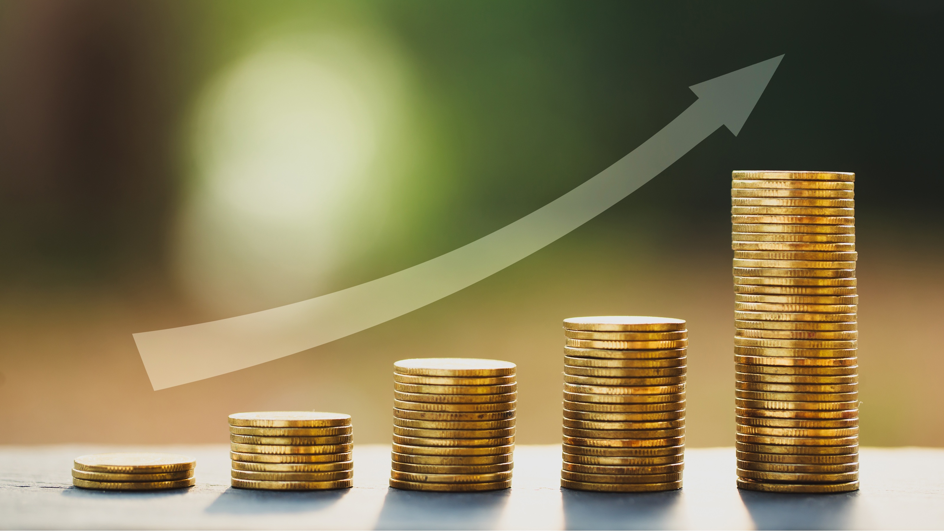 Five stacks of gold coins increasing in height with a rising arrow above them.