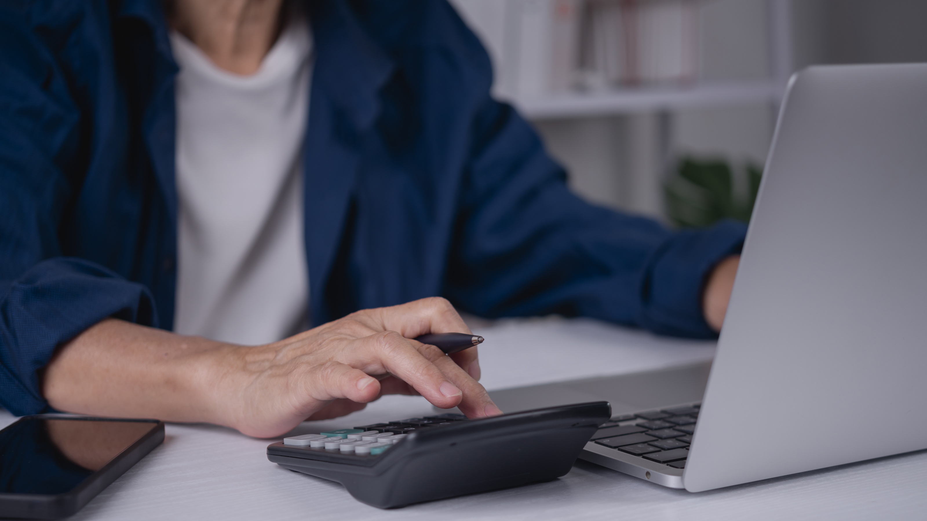 A person using a calculator to plan retirement distributions and tax impacts.
