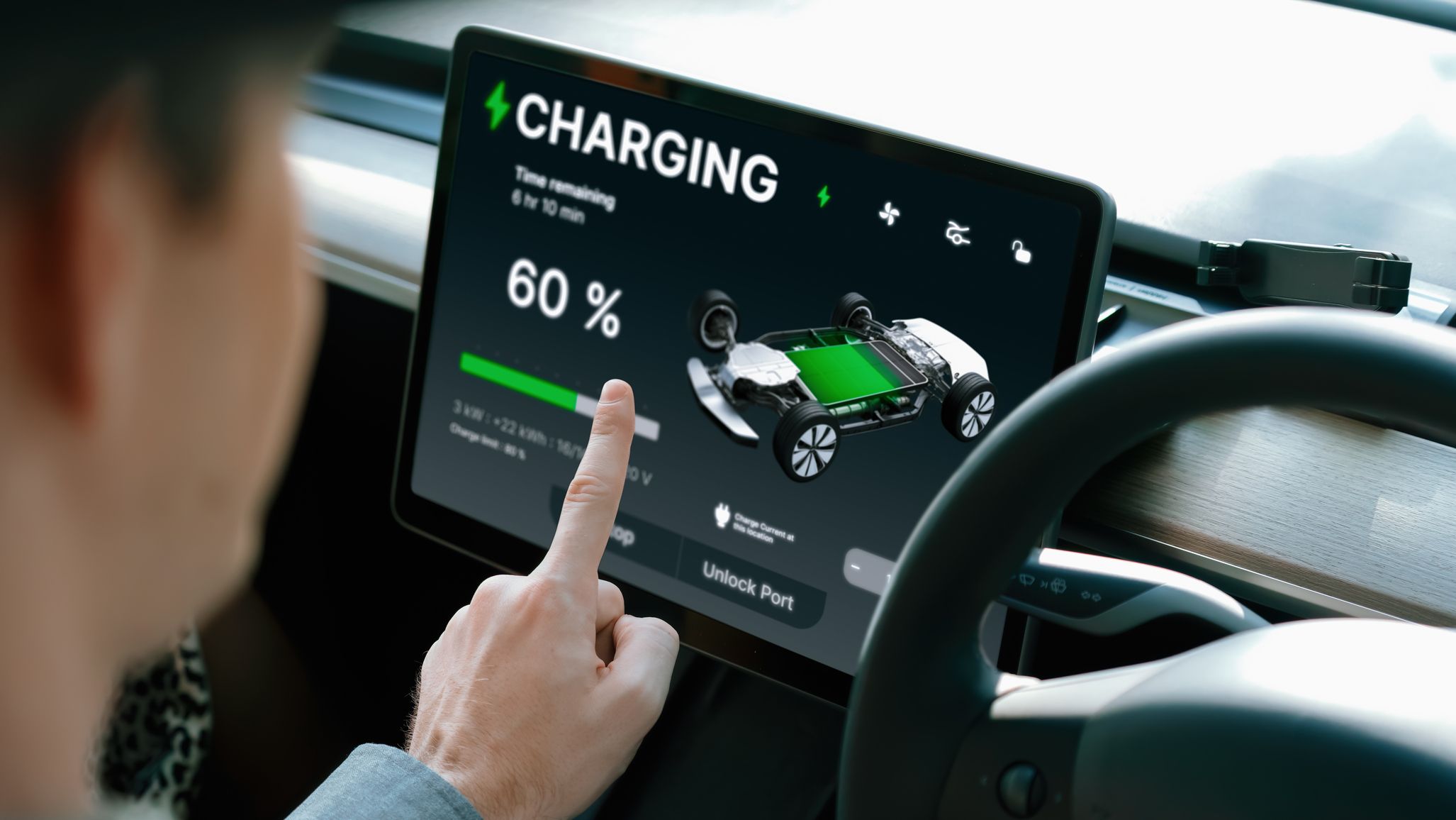 Close-up of a driver using a smartphone app to check the charging progress and battery range of an electric car.