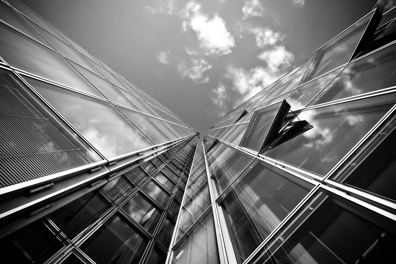 Corner of a modern glass skyscraper reflecting a clear blue sky, symbolizing corporate stability.